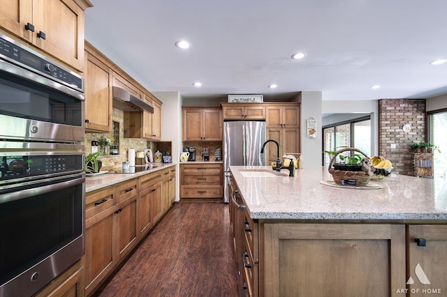 kitchen featuring sink, dark wood-type flooring, decorative backsplash, light stone countertops, and black appliances