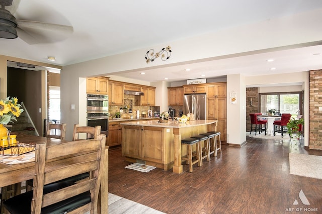 kitchen featuring stainless steel appliances, dark hardwood / wood-style floors, tasteful backsplash, a kitchen island with sink, and ceiling fan