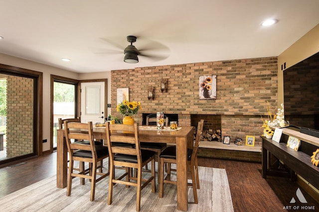 dining area featuring ceiling fan, wood-type flooring, and brick wall