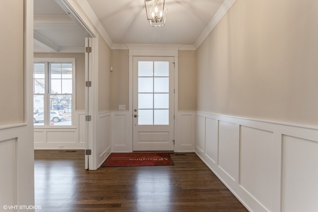 foyer entrance with ornamental molding, an inviting chandelier, and dark hardwood / wood-style floors