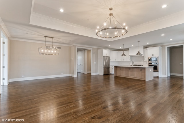 unfurnished living room featuring a raised ceiling, a chandelier, dark hardwood / wood-style flooring, ornamental molding, and sink