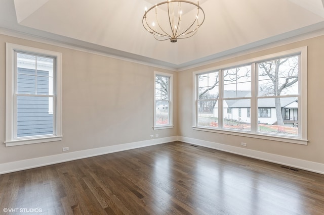 unfurnished room featuring a notable chandelier, a tray ceiling, and dark wood-type flooring