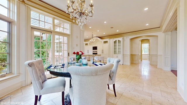 dining room featuring ornamental molding, a wealth of natural light, and a notable chandelier