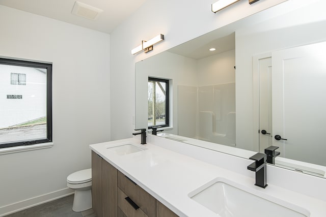 bathroom featuring dual vanity and toilet