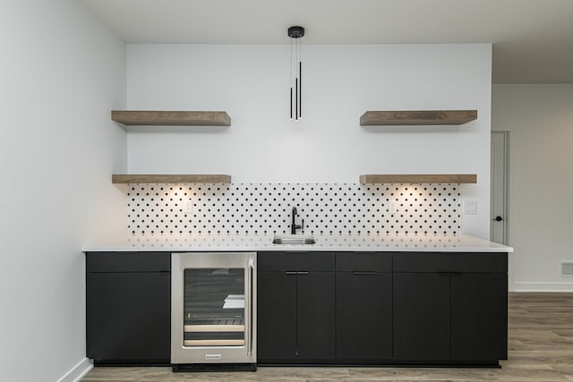 kitchen featuring sink, wine cooler, light wood-type flooring, and hanging light fixtures