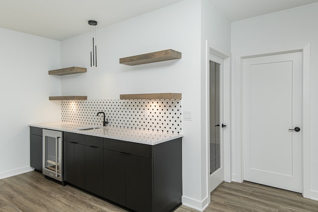 bar with sink, decorative light fixtures, light hardwood / wood-style flooring, and beverage cooler