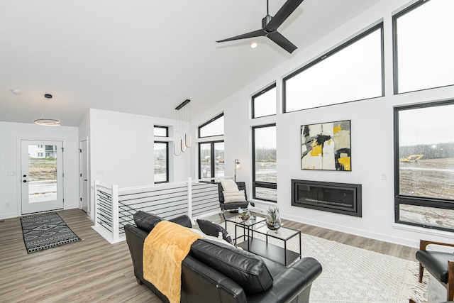 living room with high vaulted ceiling, ceiling fan, and light wood-type flooring