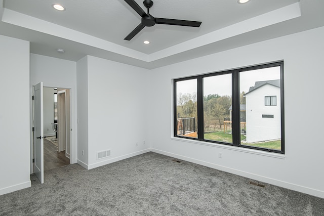 empty room with carpet, a raised ceiling, and ceiling fan