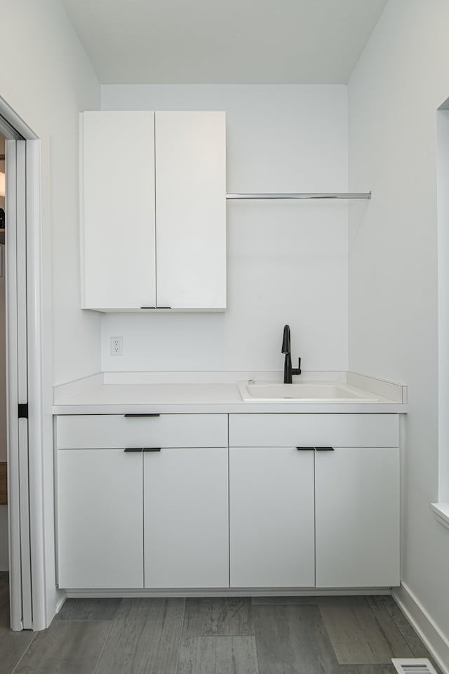 bar with sink, hardwood / wood-style floors, and white cabinets