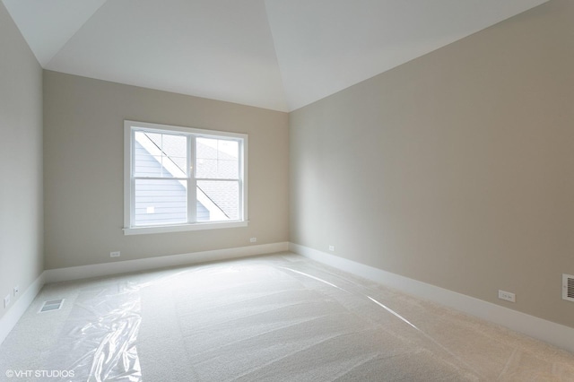 carpeted spare room with vaulted ceiling