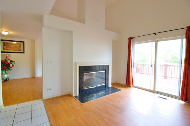 unfurnished living room with light wood-type flooring and a tile fireplace