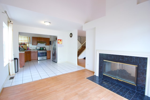 living room with a tiled fireplace and light wood-type flooring