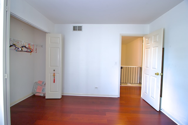 unfurnished bedroom featuring dark wood-type flooring and a closet