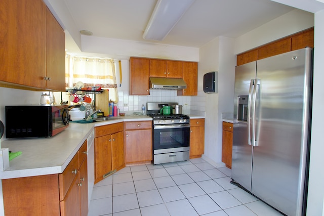 kitchen with light tile patterned flooring, sink, backsplash, and appliances with stainless steel finishes