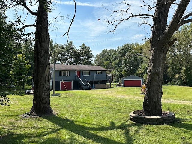 view of yard with a garage, driveway, stairway, a deck, and an outdoor structure