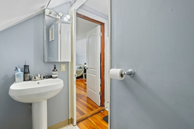 bathroom featuring a sink, wood finished floors, and vaulted ceiling