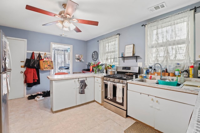kitchen featuring visible vents, stainless steel gas range oven, a sink, a peninsula, and white cabinetry