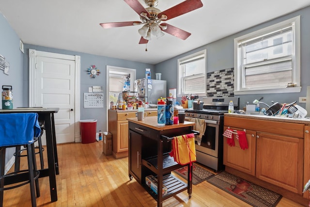 kitchen with ceiling fan, appliances with stainless steel finishes, brown cabinets, light countertops, and light wood finished floors