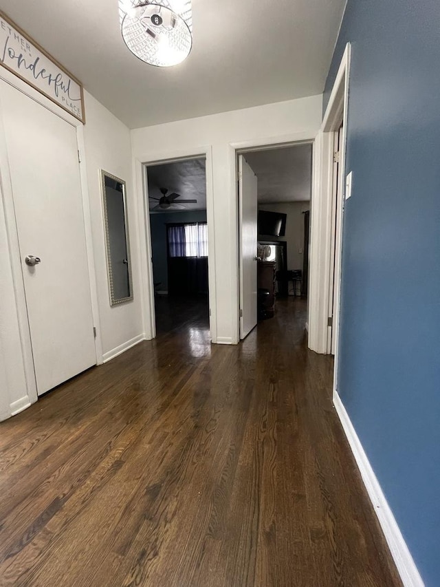 hallway with baseboards and dark wood-style flooring