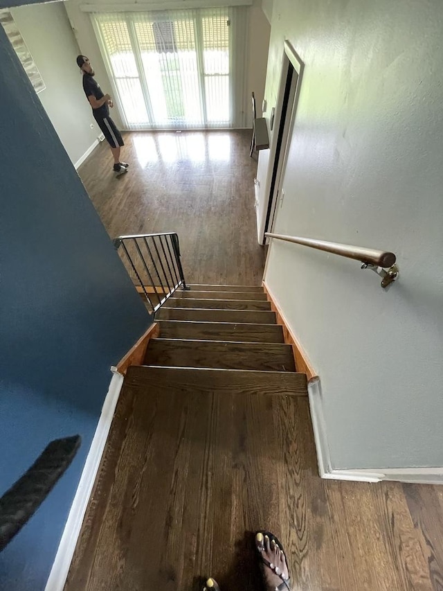 stairway with wood finished floors and baseboards