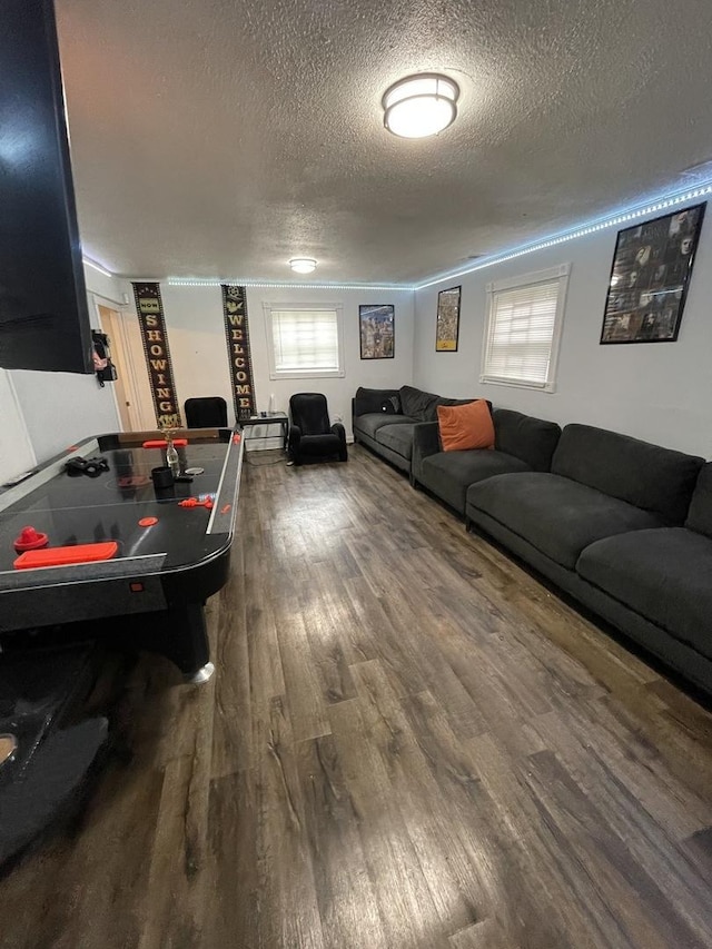 playroom with a textured ceiling and dark wood-type flooring