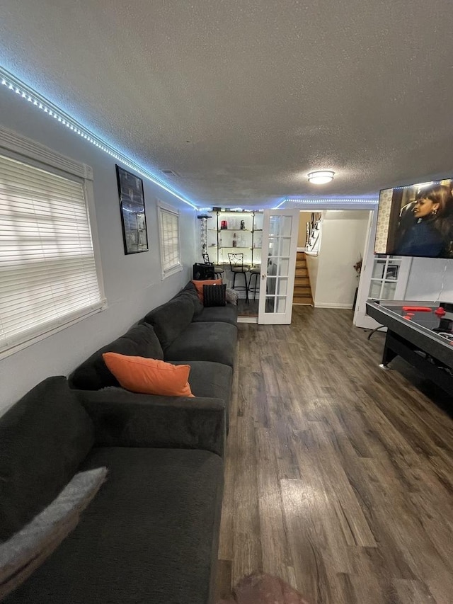 living area with a textured ceiling, stairs, and wood finished floors