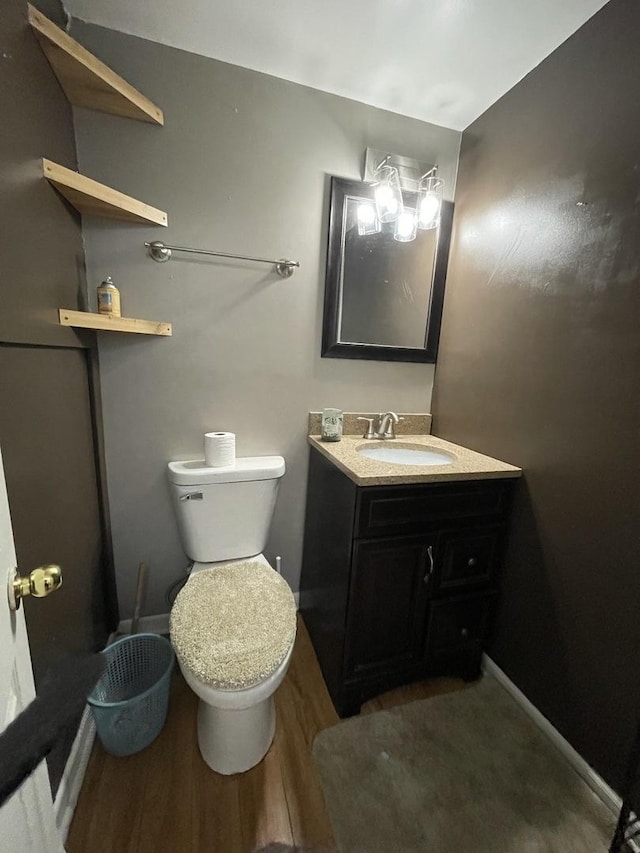 bathroom with toilet, wood finished floors, vanity, and baseboards