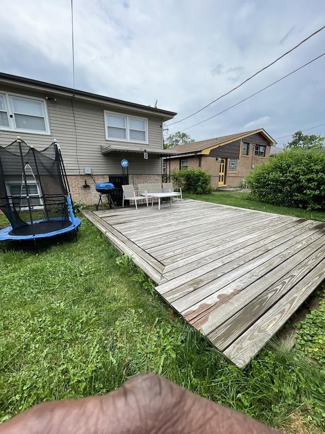 wooden deck with a trampoline and a yard