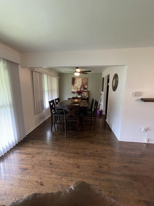 dining space featuring dark wood-style floors, ceiling fan, and baseboards