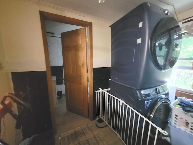 washroom with crown molding and stacked washer and clothes dryer