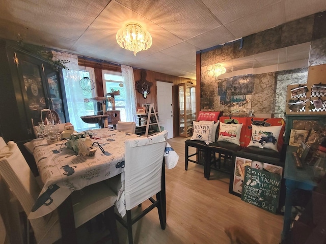 dining room featuring hardwood / wood-style flooring, wooden walls, and a chandelier