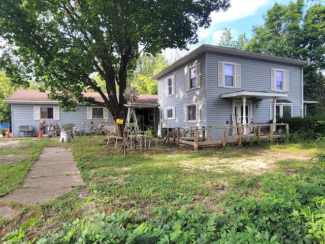 back of house with a deck and a lawn