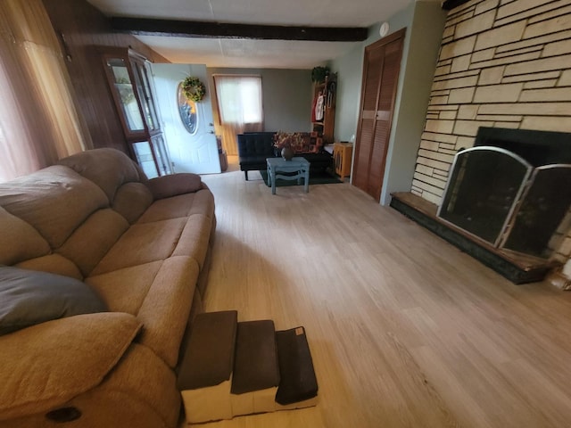 living room with a fireplace, beam ceiling, and light hardwood / wood-style floors