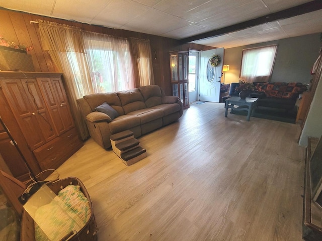 living room featuring wood-type flooring, beam ceiling, and wood walls