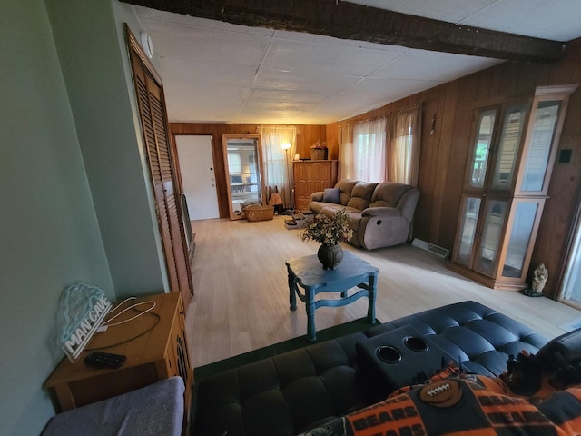 living room featuring beamed ceiling, light hardwood / wood-style floors, and wood walls