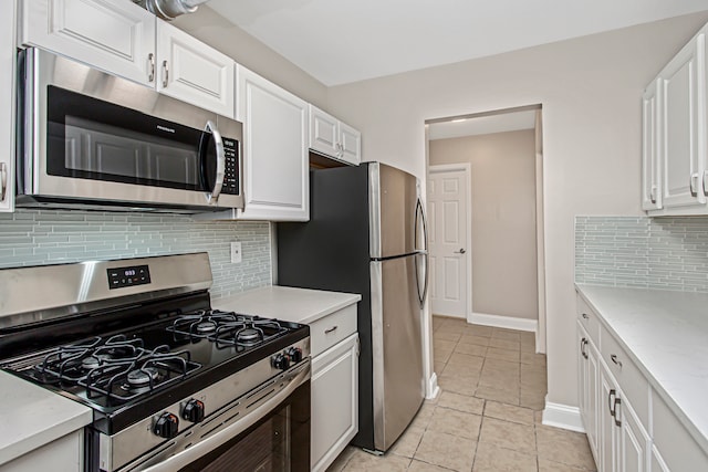 kitchen featuring appliances with stainless steel finishes, light tile patterned flooring, decorative backsplash, and white cabinetry