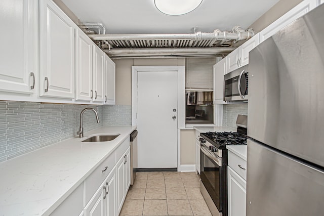 kitchen with tasteful backsplash, white cabinets, appliances with stainless steel finishes, light tile patterned floors, and sink