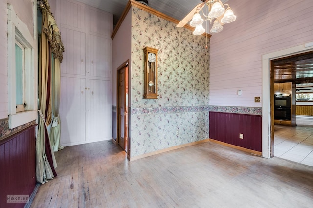 empty room with baseboards, wood-type flooring, and wallpapered walls