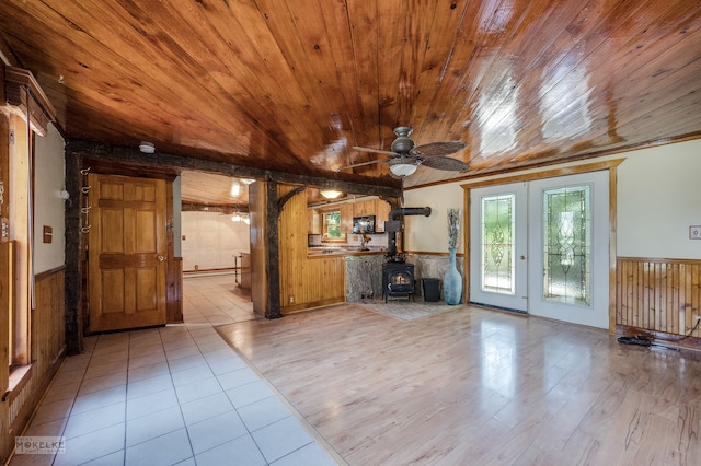 unfurnished living room featuring wood ceiling, light hardwood / wood-style flooring, ceiling fan, and a wood stove