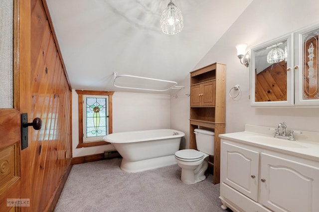 full bathroom with a freestanding bath, toilet, vanity, and vaulted ceiling