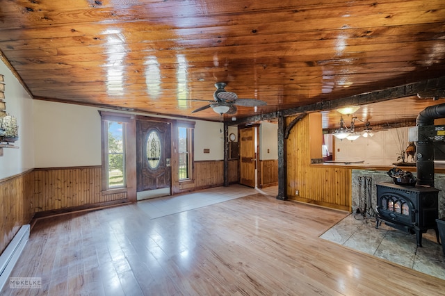 foyer entrance with ceiling fan, a wood stove, hardwood / wood-style floors, wooden ceiling, and a baseboard heating unit