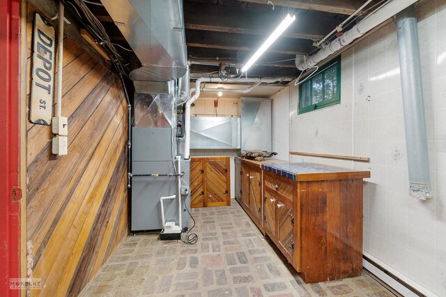 basement featuring a baseboard heating unit and heating unit