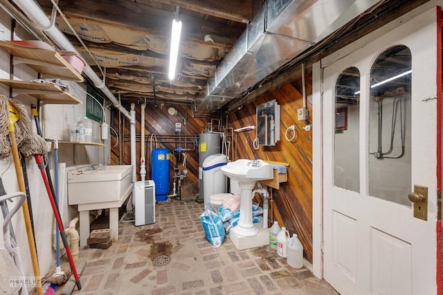 unfinished basement with wooden walls, brick floor, and a sink