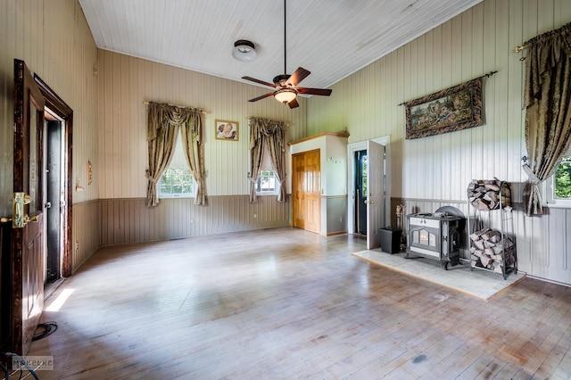 interior space with wood-type flooring, ceiling fan, and a wood stove