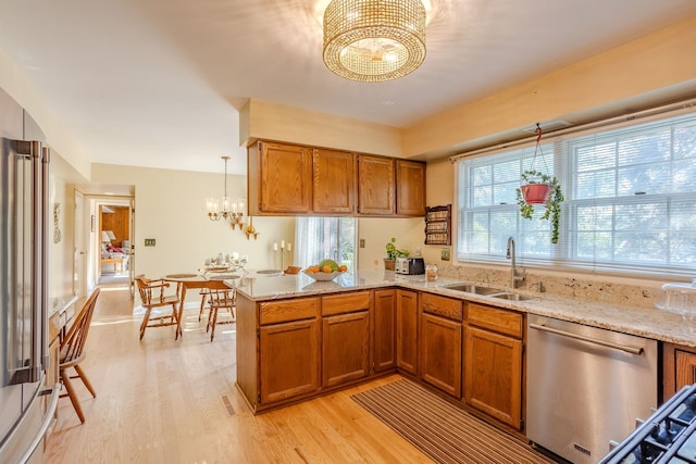 kitchen with dishwasher, light hardwood / wood-style flooring, sink, light stone counters, and kitchen peninsula