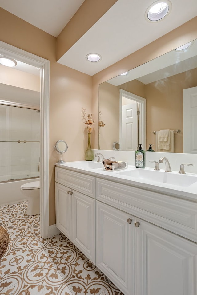 full bathroom featuring combined bath / shower with glass door, tile patterned flooring, double sink vanity, and toilet