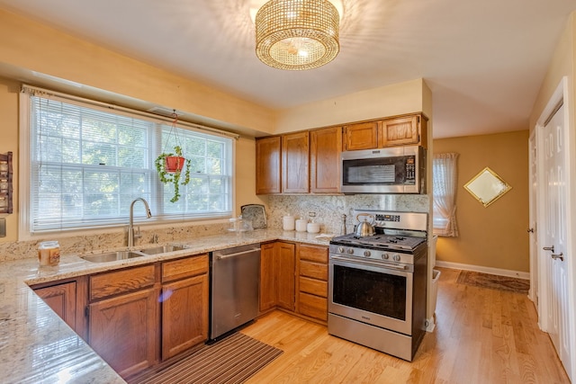 kitchen featuring sink, light wood-type flooring, appliances with stainless steel finishes, and light stone counters