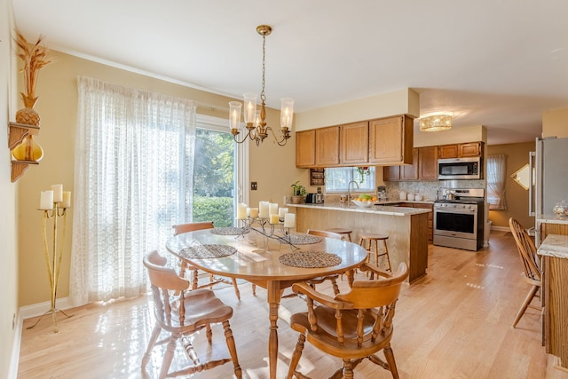 dining area featuring sink, an inviting chandelier, and light hardwood / wood-style flooring