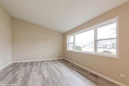 unfurnished room with lofted ceiling, wood finished floors, and baseboards