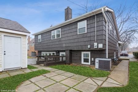 rear view of property with central AC and a chimney